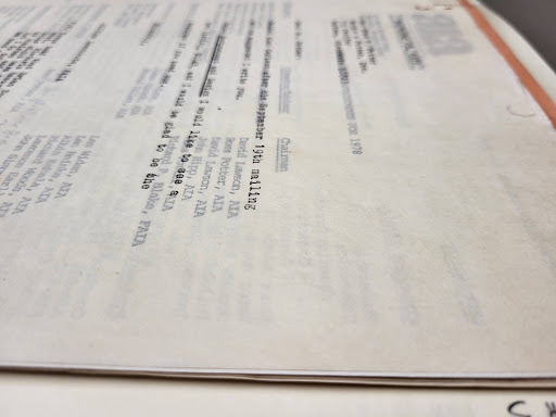 A close-up, angled photograph of a typed document on off-white onionskin paper, showing its semitransparent quality with text showing through from the page beneath.